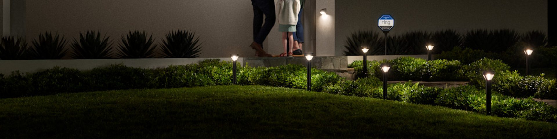 an assortment of ring smart lighting products lighting up a homeowners front yard at night 1920w480h